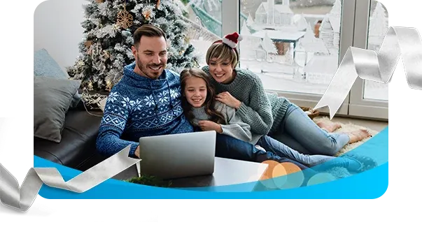 Happy family wearing holiday sweaters looking at laptop